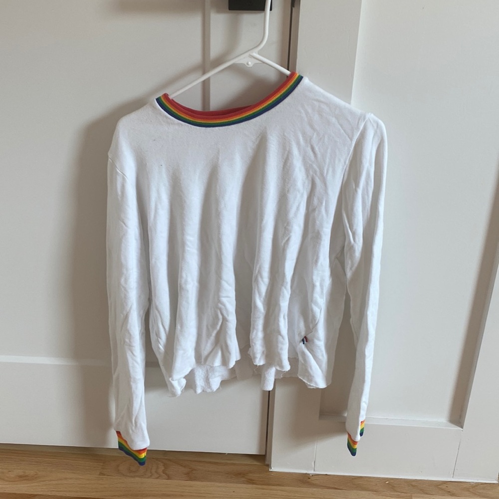 This is a cute comfy sweater that is white and has rainbow strips.